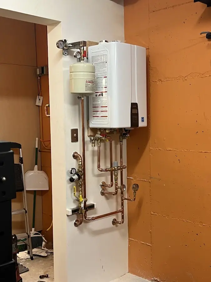 Plumbing technician inspecting water heater connections in Emmaus